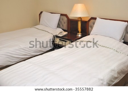 Twin beds with table lamps lighted up in a high class hotel room