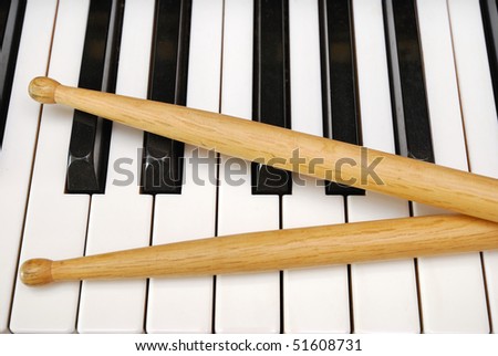 Drum sticks on black and white piano keyboard. For concepts like music and creativity.
