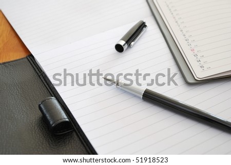 Black pen on blank writing pad or planner signifying concepts such as office and business, and work related objects
