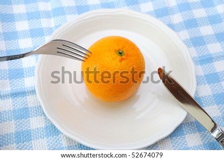 Eating orange on plate with fork and knife. Healthy eating and lifestyle, diet and nutrition, and fresh fruit concepts .