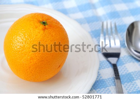 Closeup of orange on plate with utensils. Healthy eating and lifestyle, diet and nutrition, and fresh fruit concepts .