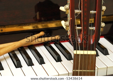 Drum sticks, guitar and piano keyboard. For concepts like music composition and creativity.