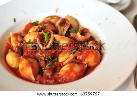 Pasta cooked with thick tomato puree and served on white plate.