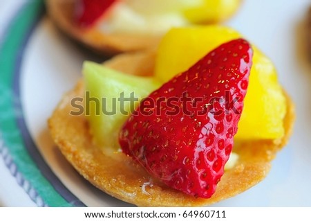 Healthy fruit tarts prepared with different colored cut fruits such as strawberries and honey dew.
