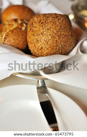 Brown buns and plate on a luxurious table layout in a restaurant.