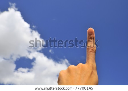 Hand of young male pointing index finger on right of frame with blue sky background.