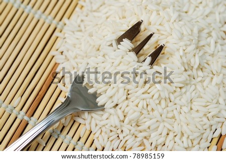 Fork in pile of freshly harvested white rice, staple diet in Asia.