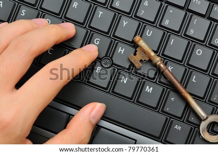 Hand and rusty antique key on black keyboard.