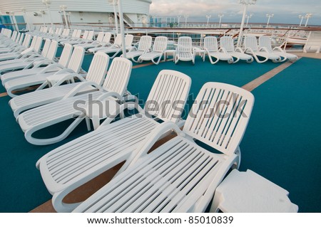Many sun tanning beach chairs on top deck of cruise ship.
