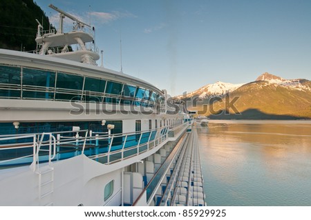 Cruise ship anchored at harbor with beautiful sunrise on background mountains.