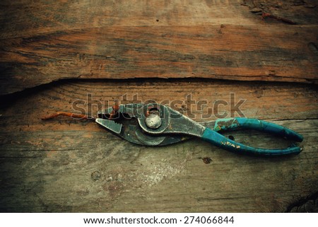 old pliers with a rusty nail on a background of the old wooden fence