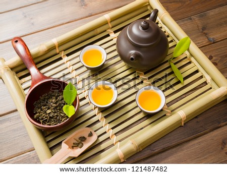 teapot,tea cup and tea leaves on a bamboo mat