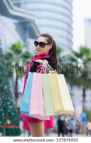 happy Chinese woman with shopping bags in business street
