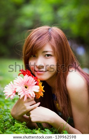 Chinese beauty with colorful Africa daisy in the forest