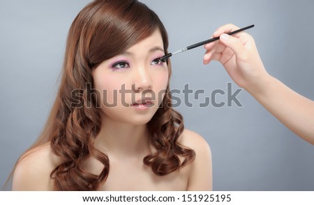 Chinese beauty with professional makeup with brush in photography studio