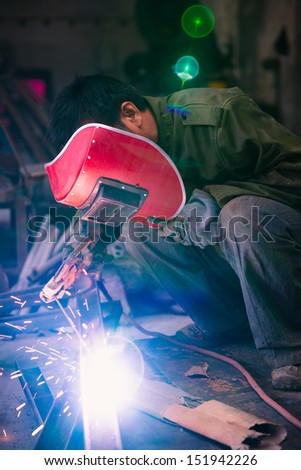 Chinese worker welding metal in a workshop