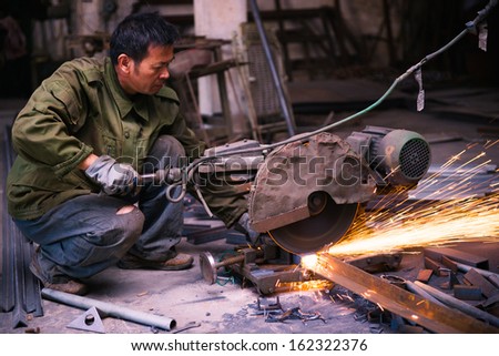 Chinese worker cutting industrial materials with machine  in a workshop