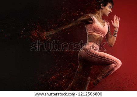 Fitness and sport motivation.. Strong and fit athletic, woman sprinter or runner, running on red background in the fire wearing sportswear.