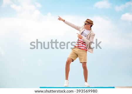 fashion man in hat and glasses pointing on copy space