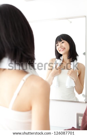 attractive asian woman looking mirror with towel in the bath room