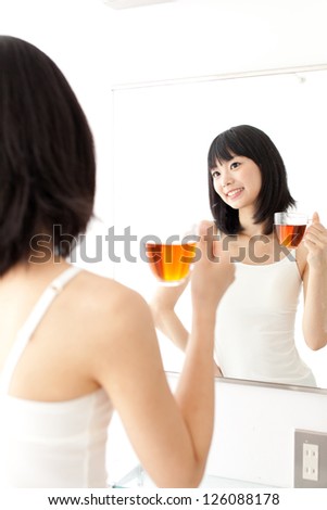 attractive asian woman drinking a tea in the bath room