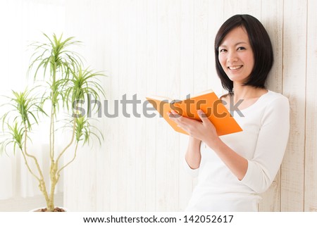 a young asian woman reading book in the room