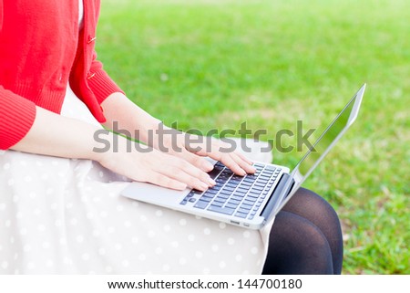 attractive asian woman  using laptop in the park