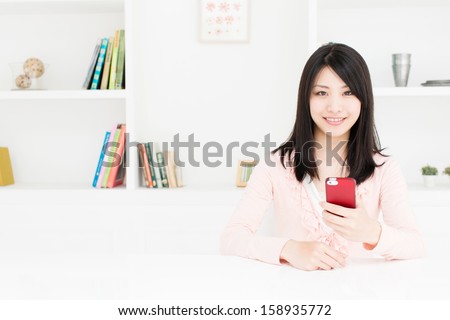 young asian woman using smart phone behind book shelf