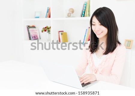 young asian woman using laptop behind book shelf