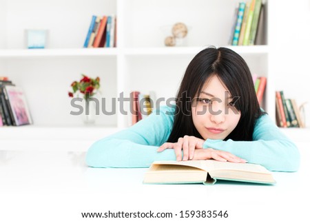 young asian woman relaxing behind book shelf