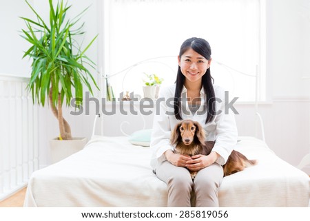 asian woman hugging miniature dachshund on the bed room