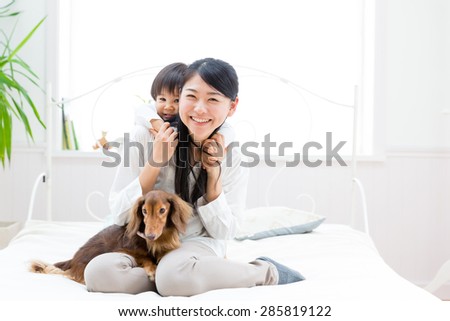 asian familiy and miniature dachshund relaxing on the bed room