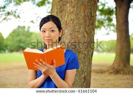 young woman reading a book in the park