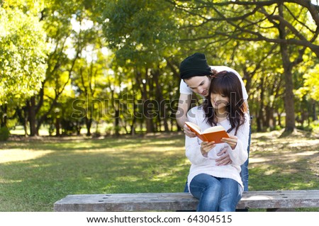 young couple reading a book on park bench
