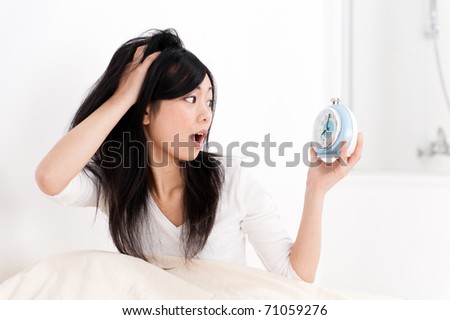 a portrait of beautiful asian woman looking at the clock on the bed