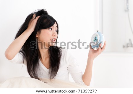 a portrait of beautiful asian woman looking at the clock on the bed