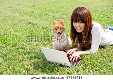 beautiful asian woman using laptop computer with dong in the park