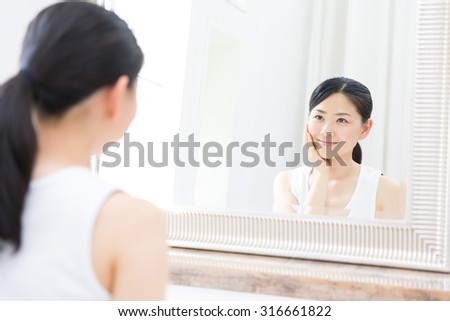 young asian woman looking mirror in the bathroom