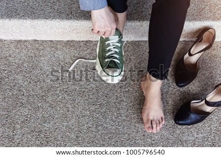 Health Care or Life Balance concept. Barefoot Business Woman sitting at stair to Changing Shoes from High Heel to Comfortable Sneaker. Top View