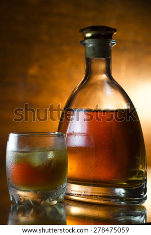 Glass with whiskey and a full whiskey bottle