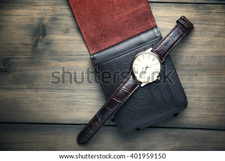 elegant watch and wallet on wooden table