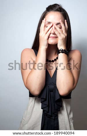 A color image of a worries woman covering her face.