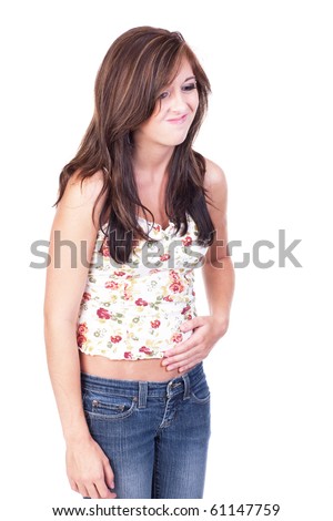 Fit teenage girl in blue jeans and flower print top, rubbing her belly and displaying a pained look on her face.