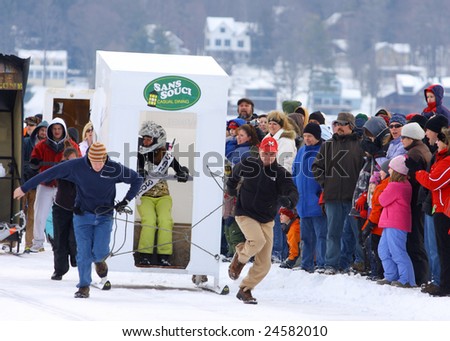 LAKE GEORGE, NY - February 7, 2009: An outhouse race team runs their hardest to win at the February 7 , 2009 Lake George Winter Carnival.