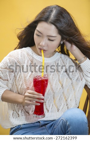 Young asian woman drinking Red tropical drink by straw