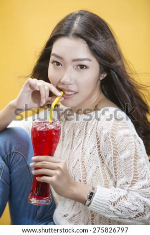 Young asian woman drinking Red tropical drink by straw