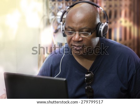 Afro man sitting and using headphones on laptop