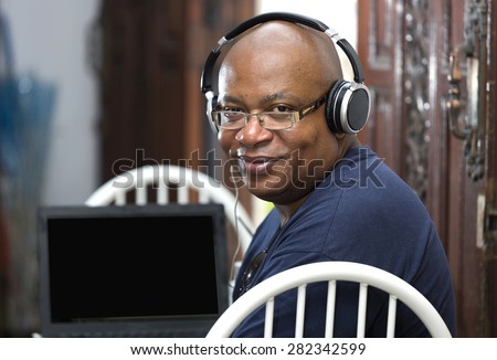 Afro man sitting and using headphones on laptop