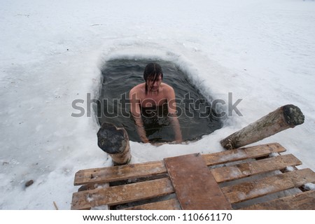 The winter swimming. man in the ice-hole.