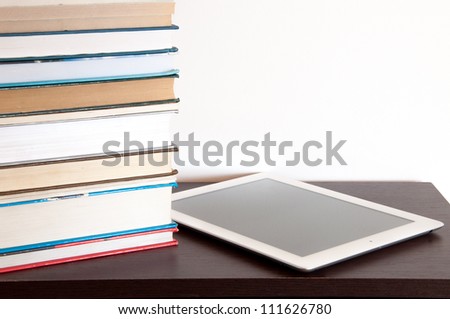 E-book reader and stack of books on a table